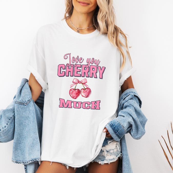 White Comfort Colors graphic tee with pink lettering, heart-shaped cherries with a bow, and the phrase “Love You Cherry Much.”