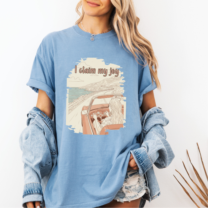 Washed Denim Comfort Colors graphic tee with a vintage-style coastal driving illustration and the phrase “I claim my joy.”
