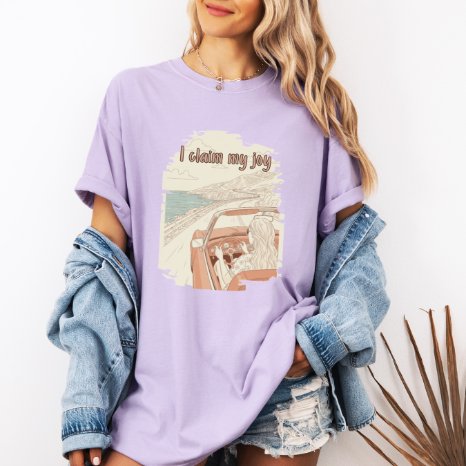 Comfort Colors graphic tee with a vintage-style coastal driving illustration and the phrase “I claim my joy.”