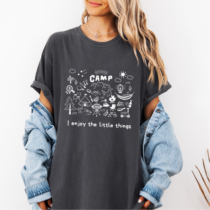 Pepper Comfort Colors graphic tee with a blue camp doodle illustration featuring outdoor icons and the phrase “I enjoy the little things”