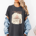 Pepper Comfort Colors graphic tee with a cozy fireplace illustration, coffee cup, socks, and the phrase “I find myself in stillness.”