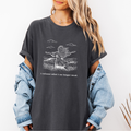 Pepper Comfort Colors graphic tee with a line art illustration of a woman standing in an open field with arms open and the phrase “I release what I no longer need.”