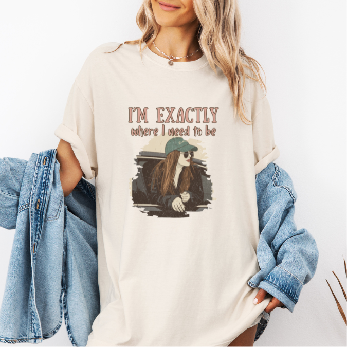 Ivory Comfort Colors graphic tee with a vintage-style illustration of a woman leaning out of a car window and the phrase “I’m exactly where I need to be.”