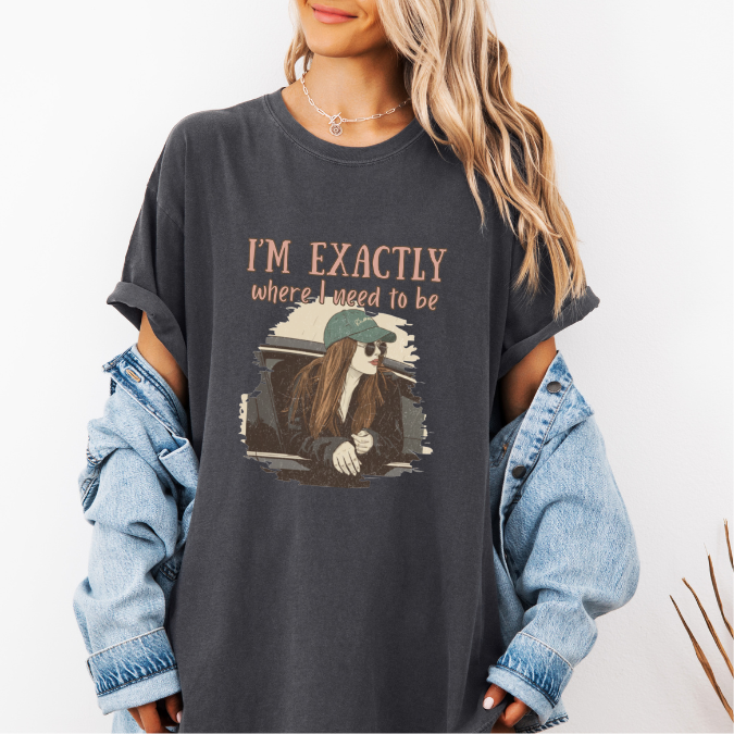 Pepper Comfort Colors graphic tee with a vintage-style illustration of a woman leaning out of a car window and the phrase “I’m exactly where I need to be.”