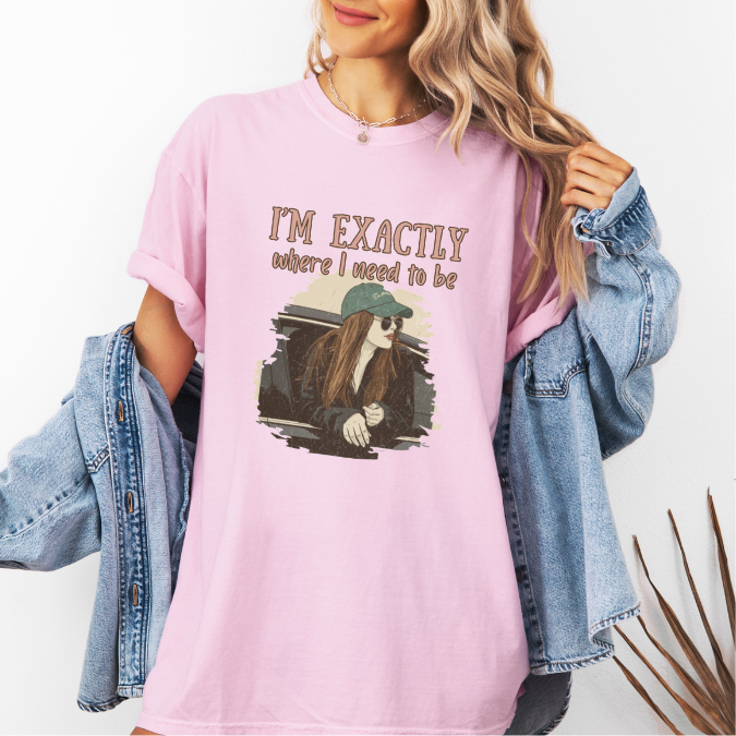 Pink Comfort Colors graphic tee with a vintage-style illustration of a woman leaning out of a car window and the phrase “I’m exactly where I need to be.”