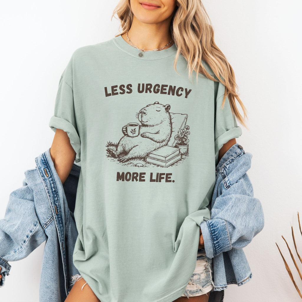 Woman wearing Less Urgency More Life capybara Comfort Colors tee in Bay green with denim jacket