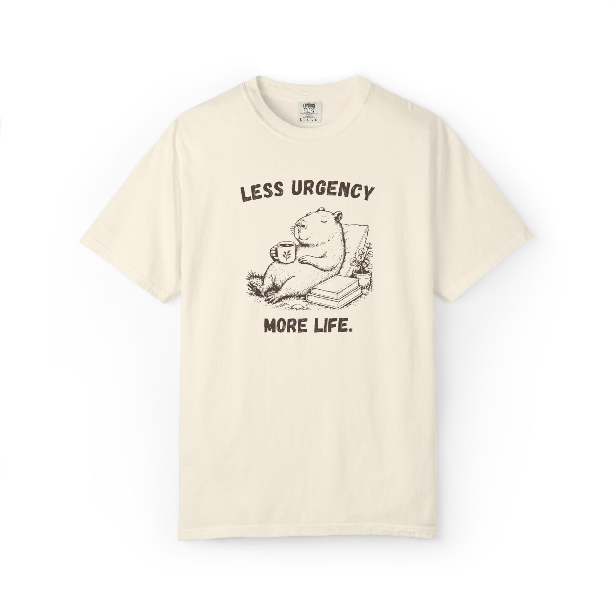 Less Urgency More Life capybara Comfort Colors tee in Ivory, flat lay product photo
