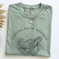 Close-up of Bay Comfort Colors tee with English sea turtle letting go quote design