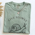 Folded Bay Comfort Colors t-shirt with the Live Slowly, Feel Deeply minimalist snail design