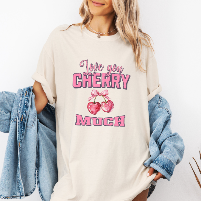 Ivory Comfort Colors graphic tee with pink lettering, heart-shaped cherries with a bow, and the phrase “Love You Cherry Much.”