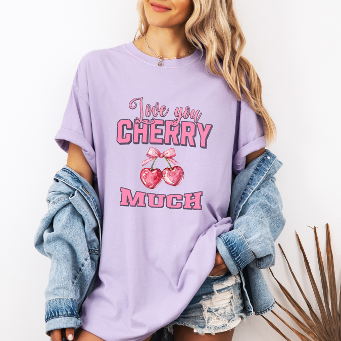 Lavander Comfort Colors graphic tee with pink lettering, heart-shaped cherries with a bow, and the phrase “Love You Cherry Much.”