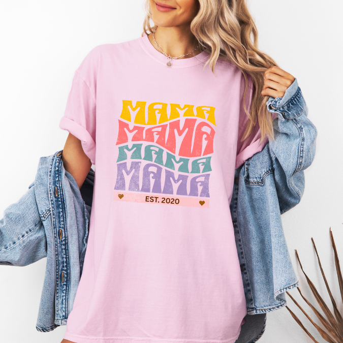 Pink Comfort Colors t-shirt with bold retro stacked MAMA lettering in yellow, pink, teal, and purple plus a customizable EST. year design for new moms
