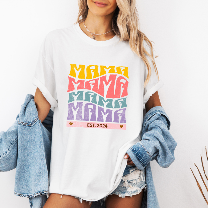 White Comfort Colors t-shirt with bold retro stacked MAMA lettering in yellow, pink, teal, and purple plus a customizable EST. year design for new moms