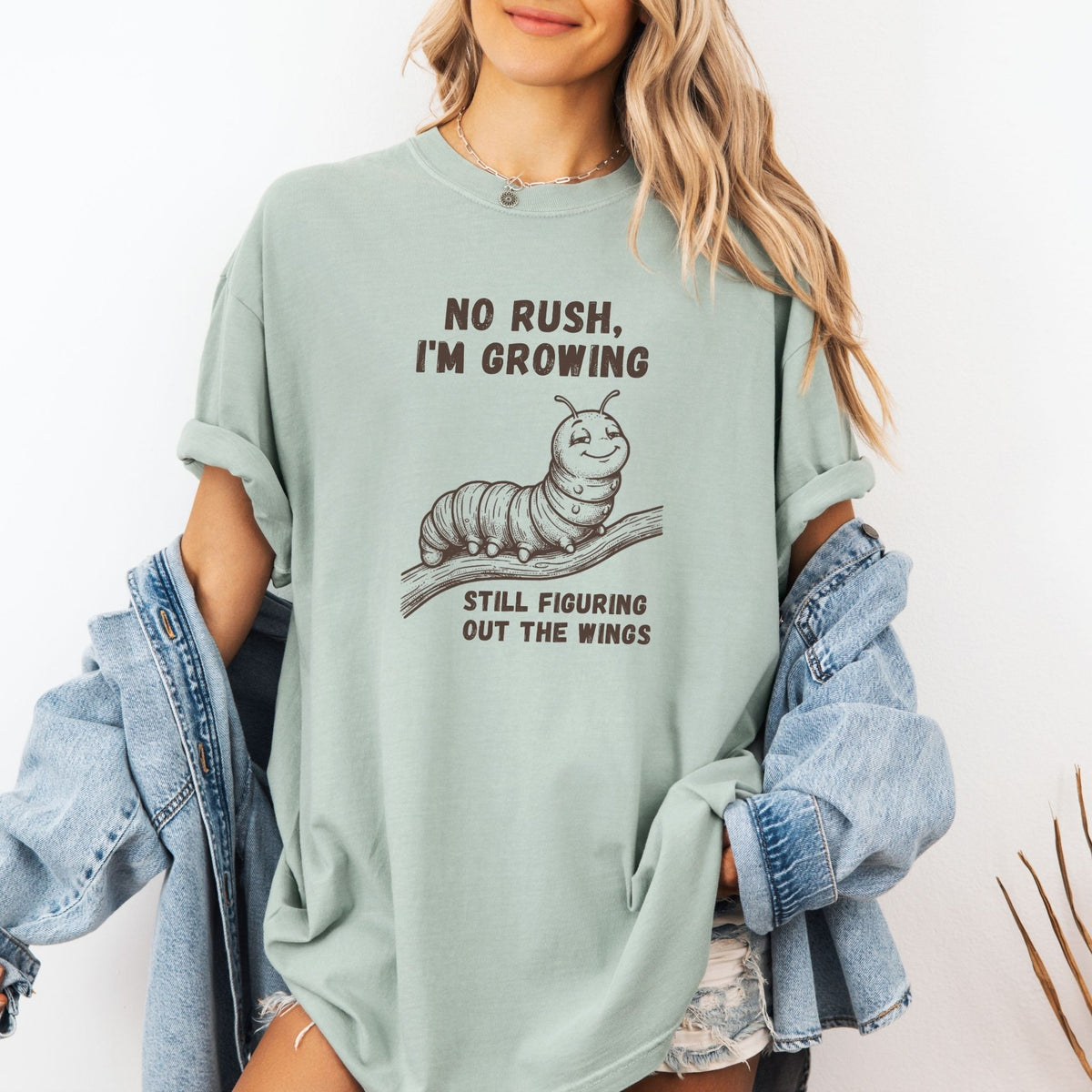 Woman wearing No Rush I'm Growing caterpillar Comfort Colors tee in Bay green with denim jacket