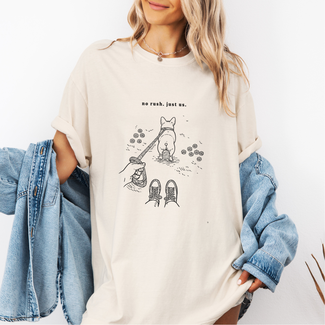 Ivory Comfort Colors graphic tee with a line art illustration of a person walking a dog and the phrase “no rush. just us.”