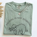 Folded Bay Comfort Colors t-shirt with the Pausing Is Not Stopping minimalist sloth design