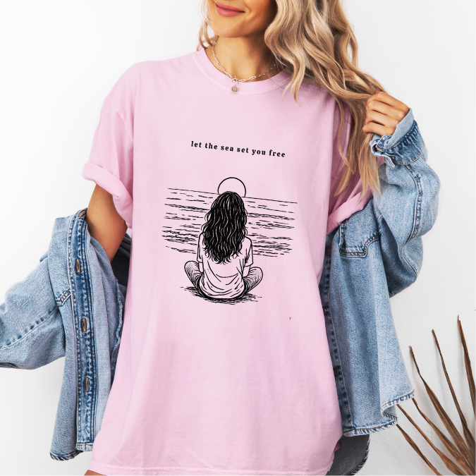 Blossom Comfort Colors graphic tee with black line art illustration of a woman sitting by the ocean – Quiet by the Sea design