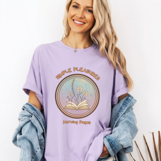 Lavender Comfort Colors graphic tee with a circular Morning Pages design featuring an open book with flowers growing from the pages.