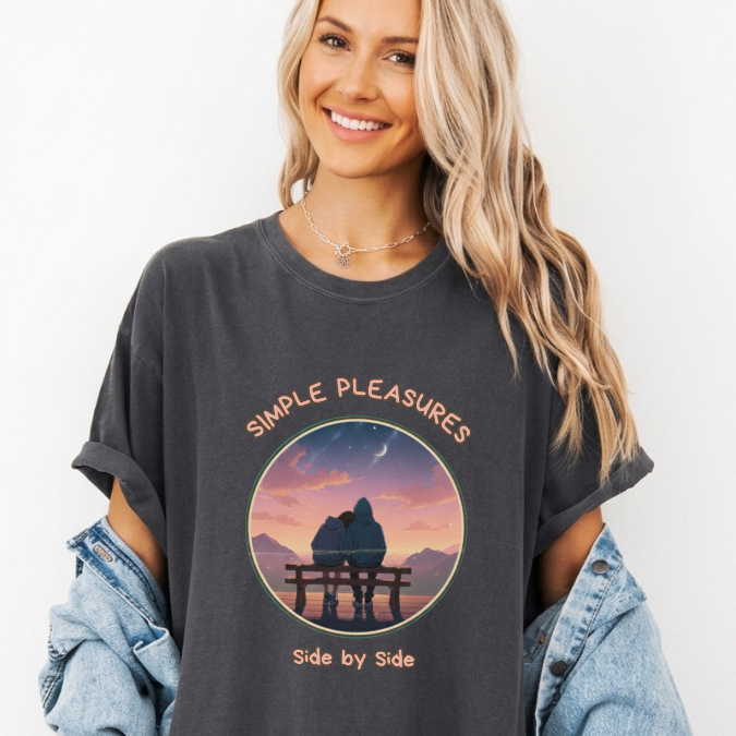 Charcoal Comfort Colors graphic tee with a circular sunset scene of two people sitting together on a bench and the phrase “Simple Pleasures Side by Side.”