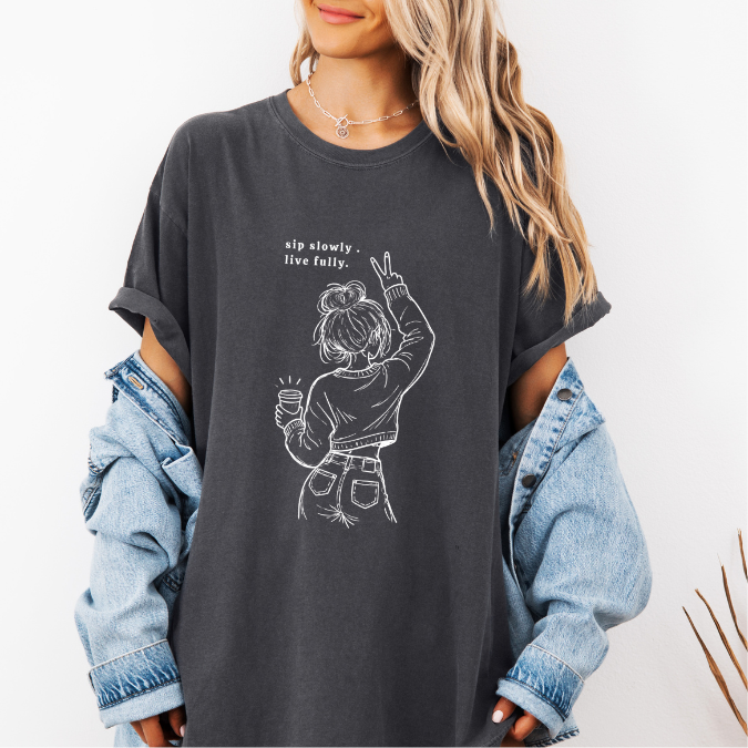 Pepper Comfort Colors graphic tee with a feminine line art illustration of a woman holding coffee and the phrase “sip slowly. live fully.”