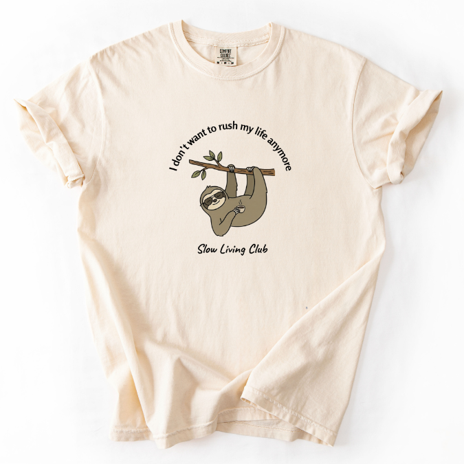 I Don't Want to Rush My Life Anymore sloth 
graphic tee in Ivory flat lay – Comfort Colors 
unisex shirt – Slow Living Club collection