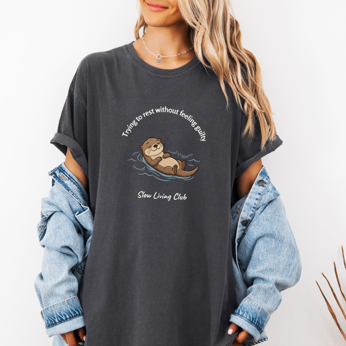 Pepper Comfort Colors shirt with relaxed otter graphic and Trying to Rest Without Feeling Guilty slow living message.
